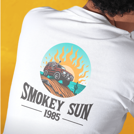 White shirt with a colorful design of a car on a desert road against an orange sun and blue sky. Text reads "Smokey Sun 1985."