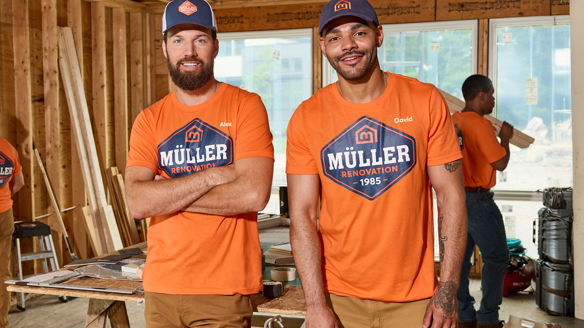 Two workers wearing custom orange T-shirts at a job site.