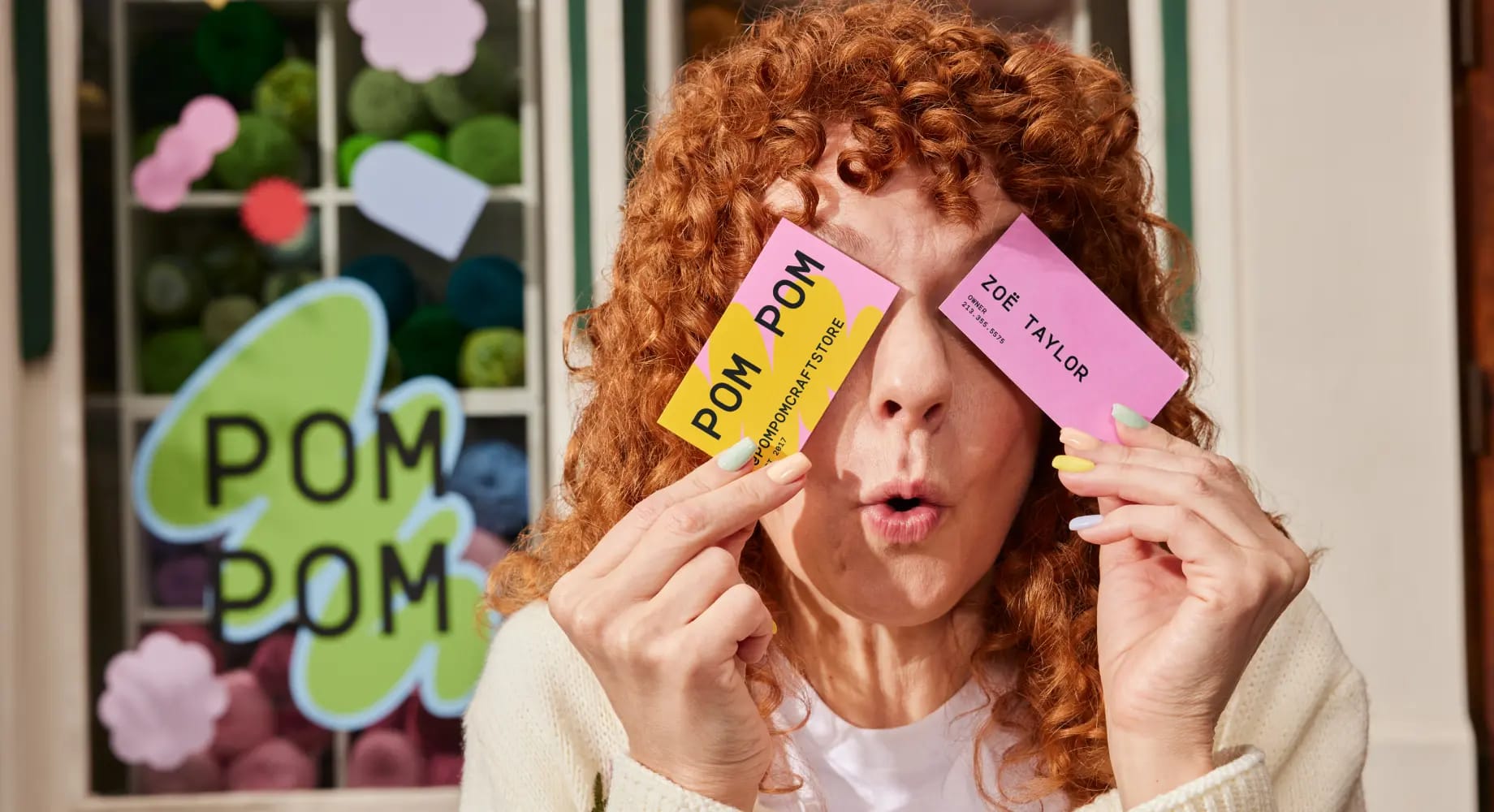 A woman business owner covering her eyes with two beautifully designed business cards printed by Vistaprint.