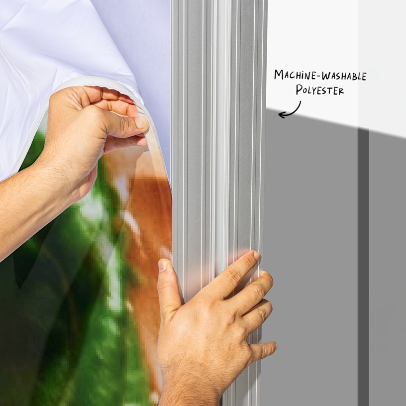 A closeup of the lightbox display wall's fabric being installed with hook-and-loop fasteners. An arrow points to the machine-washable polyester.