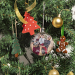 Ein Christbaum mit einer personalisierten Weihnachtsbaumkugel samt Foto eines Vater mit seiner Tochter in Winterkleidung. 