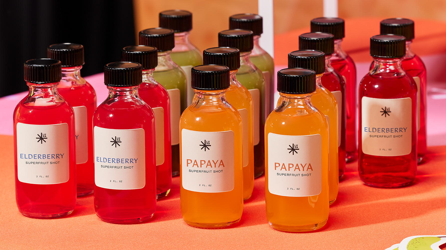Rows of brightly colored fruit drinks in glass bottles contrasting with simple white branded labels