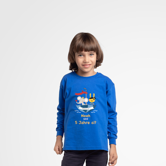 Junge mit einem blauen T-Shirt mit Bedruckung, nämlich einer bunten Illustration und einem Namen.