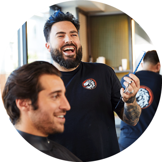 A barber wearing a black printed T-shirt personalised with a logo in the shape of a lion’s head