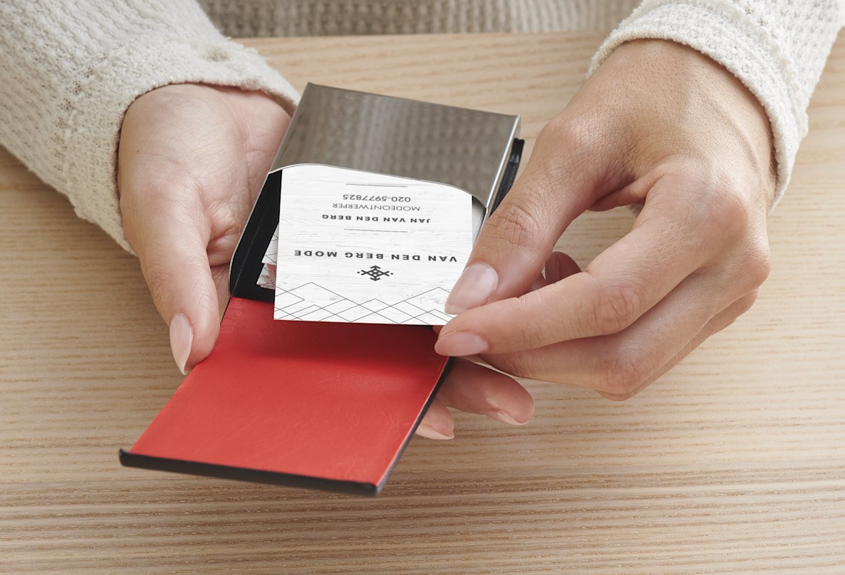 Een vrouw neemt een kaartje uit een verticale zwartleren visitekaartjeshouder.