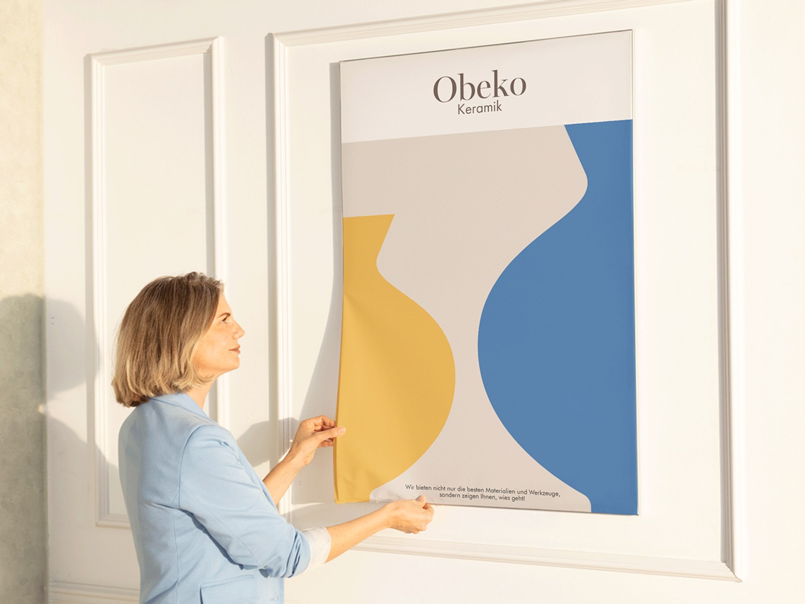 Eine Frau platziert den neuen Bannerdruck für eine Keramikwerkstatt in dem nahtlosen Rahmen.