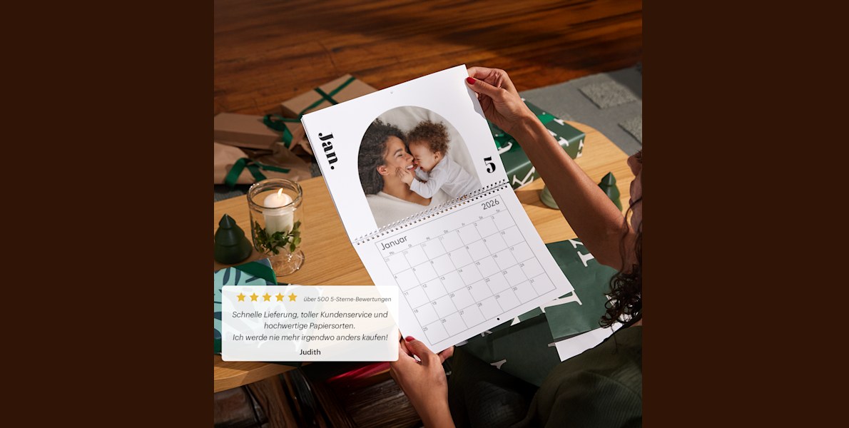Hände halten einen individuell angepassten Wandkalender mit einem Foto einer Mutter samt Baby. 