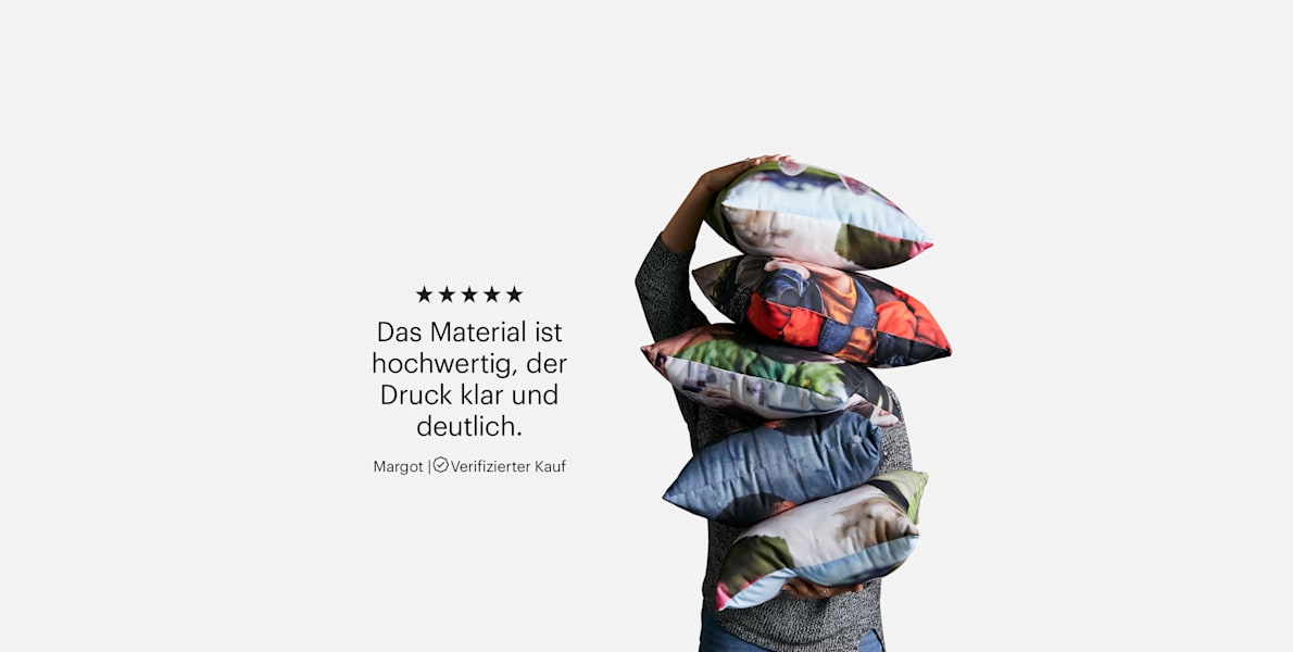 Eine Person trägt einen Stapel Fotokissen. Eine Kundenrezension, die lautet: „Das Material ist hochwertig, der Druck klar und deutlich.“