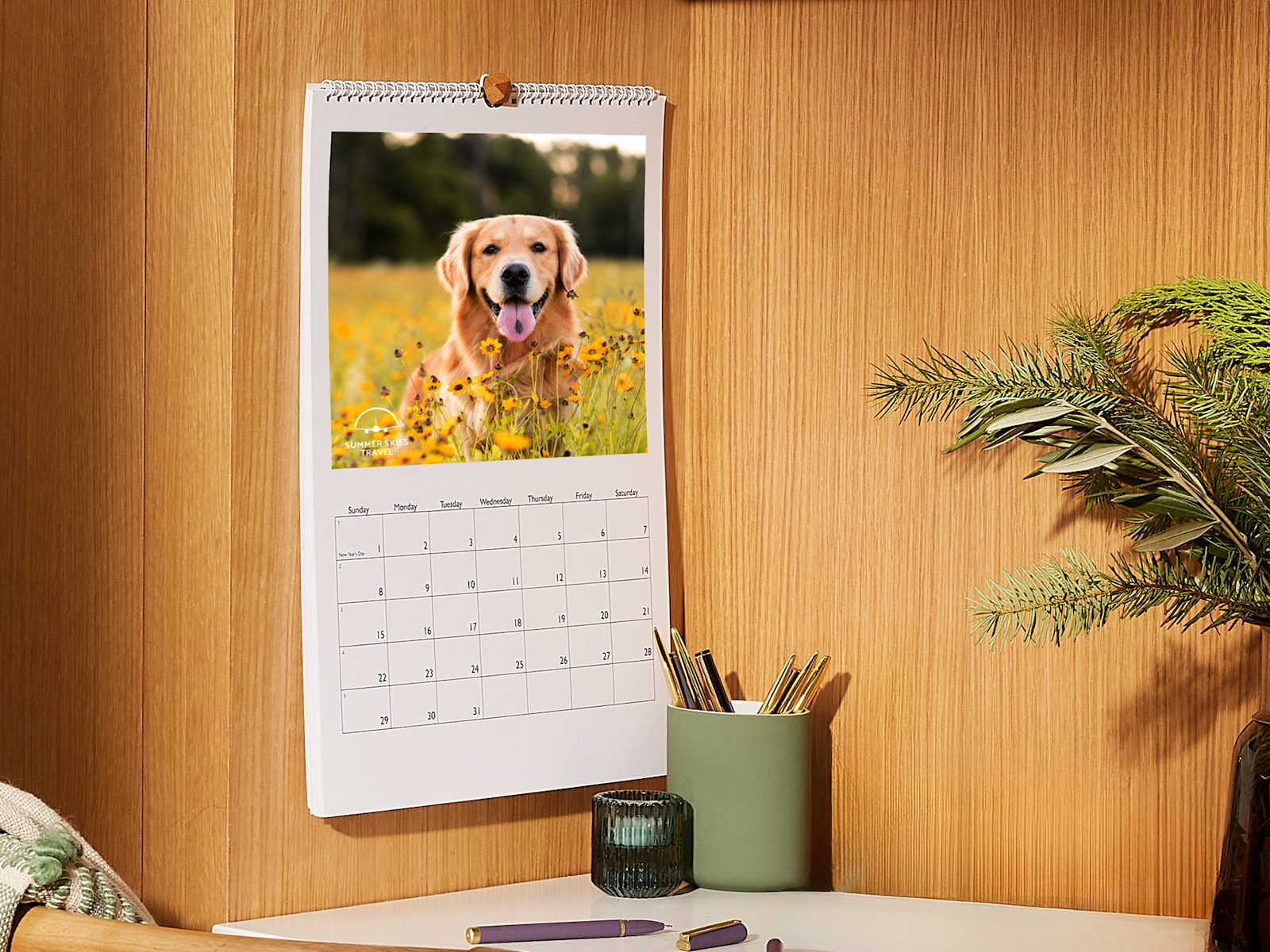 A wall calendar displayed on a wood wall and open to a picture of a golden retriever. 