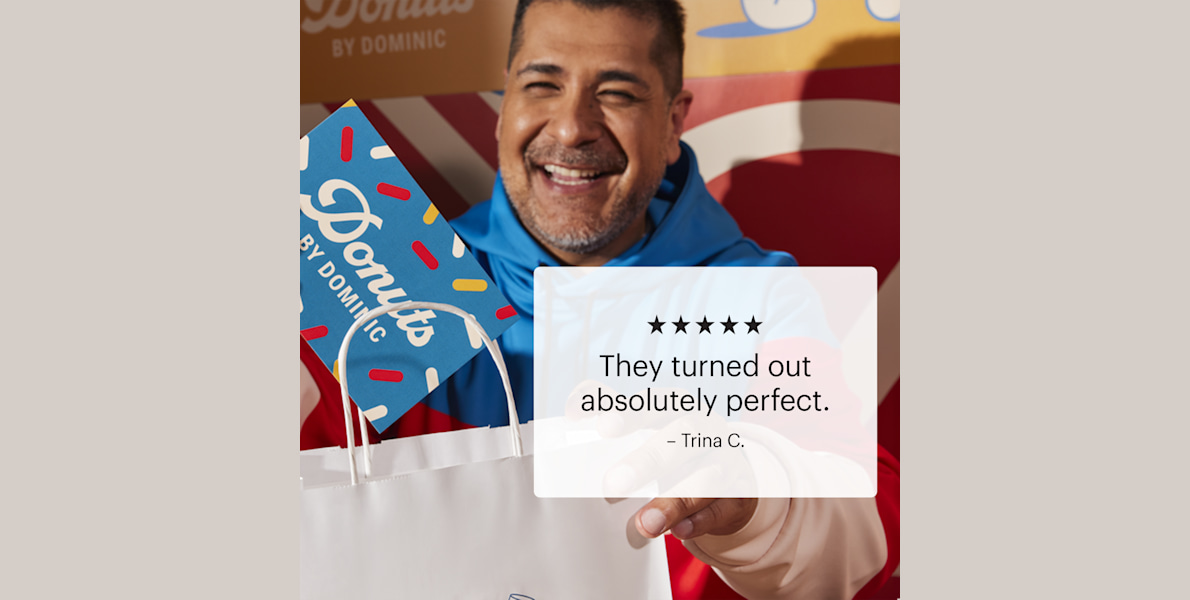 A donut shop owner placing a postcard in a takeaway bag.