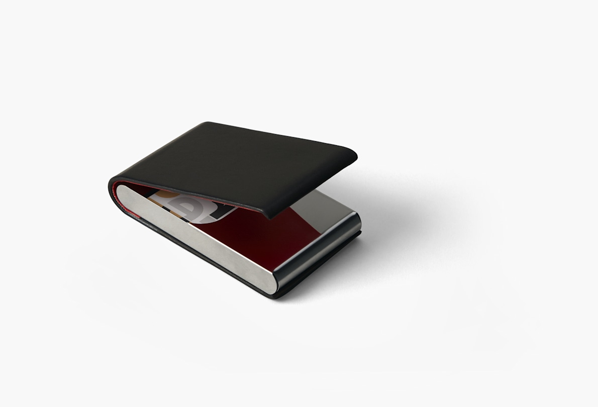 A black leather vertical business card holder slightly opened showing the cards inside. 