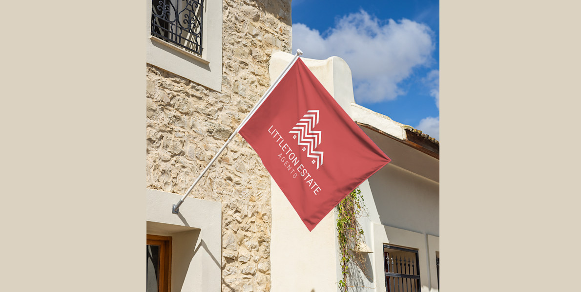 Larger version: A flag for an estate agent flying above a house.