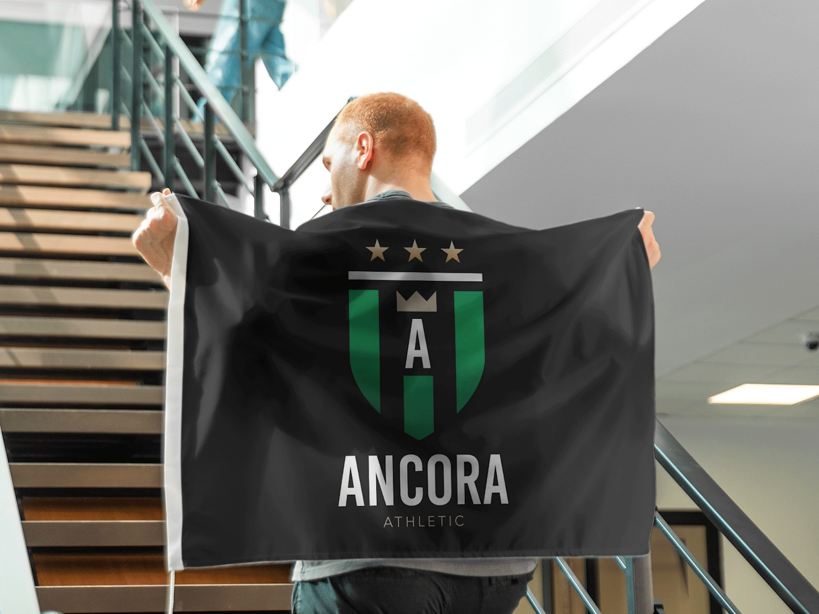 A man carrying a flag featuring a sports team’s badge.