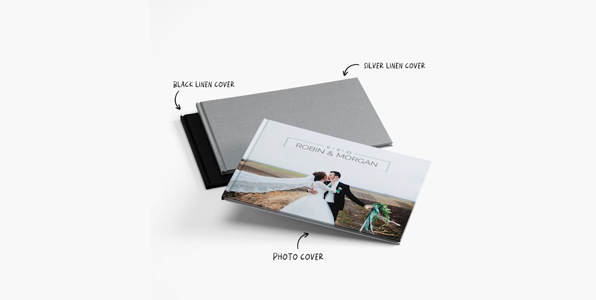 A pile of photo books featuring different cover styles: black linen, silver linen, and photo covers. 