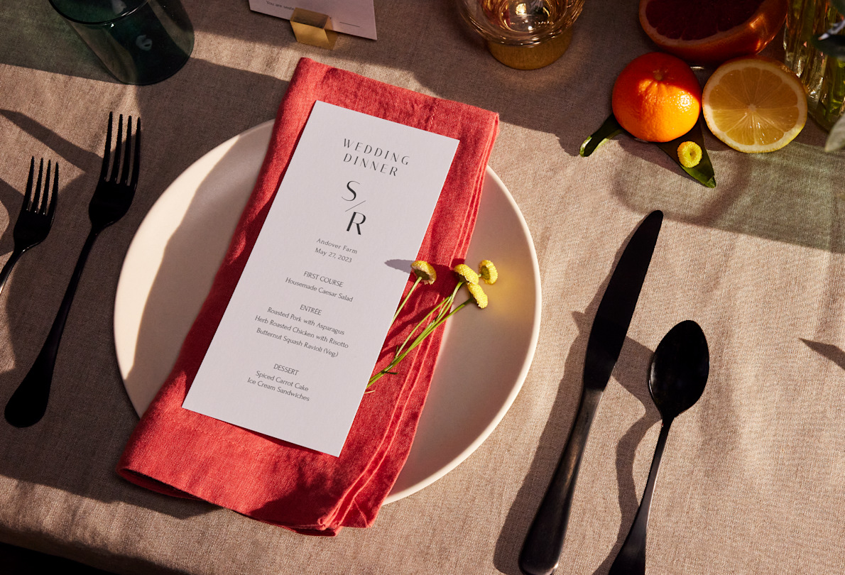 A wedding menu with black text sits on a farmhouse style table.