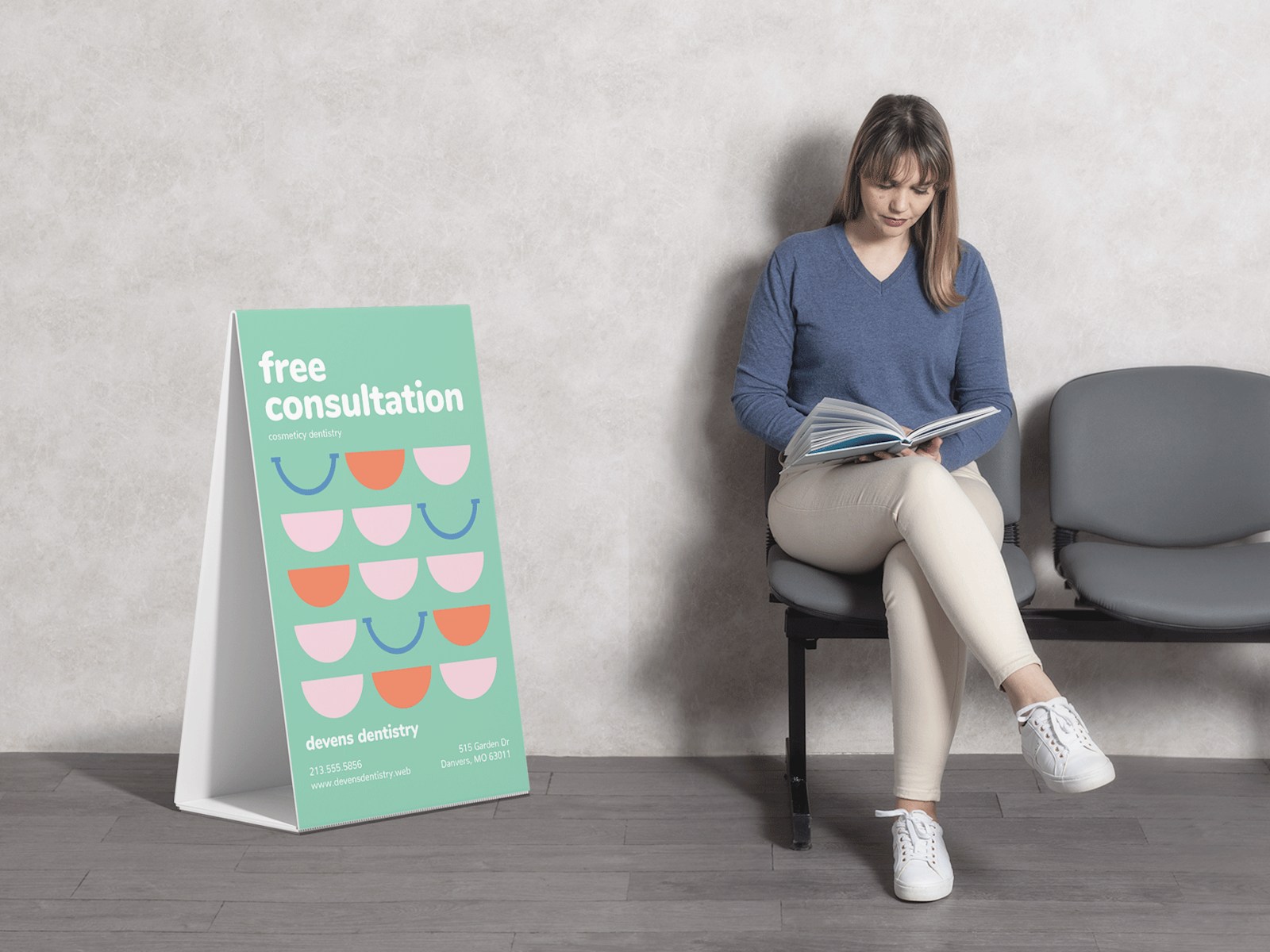 An image of a woman in a blue shirt reading while sitting in a waiting room, with a Corrugated A-frame sign promoting free consultations with a dentist.