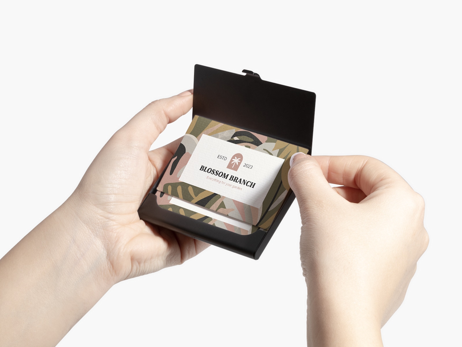 A person holding a black aluminum business card holder showing business cards for a gardening business.