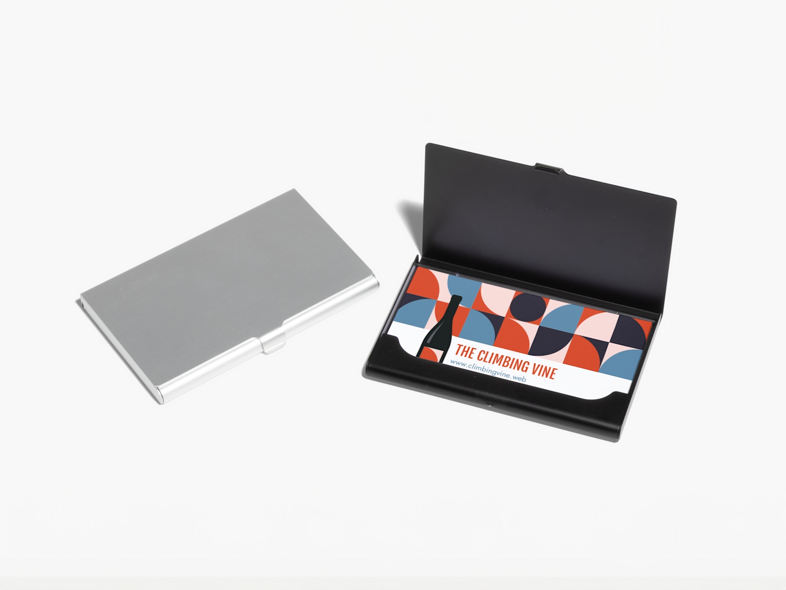A closed silver aluminum business card holder and an open black business card holder showing business cards for a wine brand.