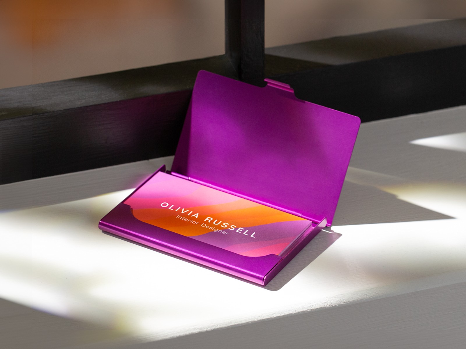 A purple aluminum business card case holding business cards for an interior designer. Purple cases are currently 20% off.