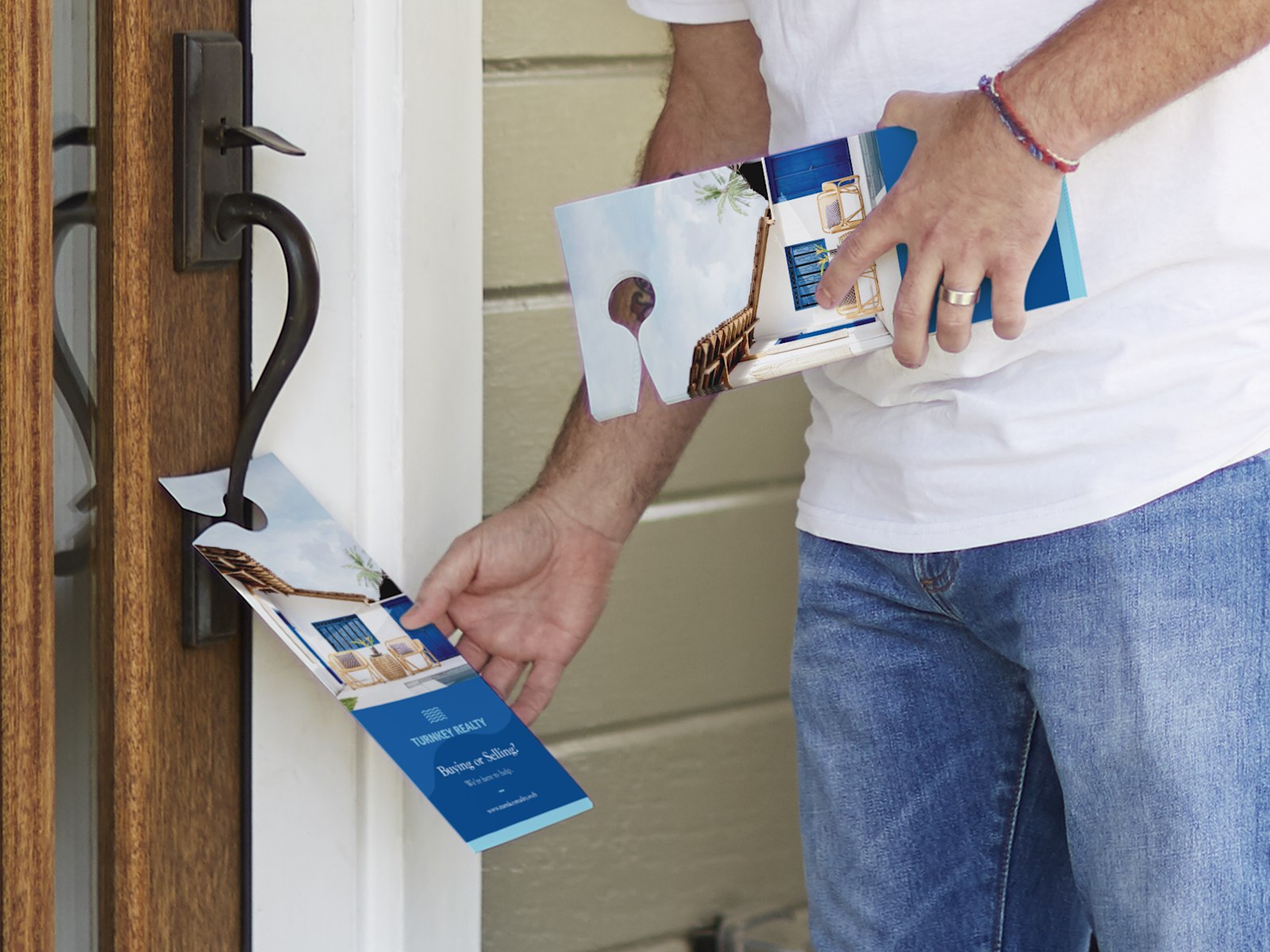 A realtor hanging door hangers promoting a real estate agency. 