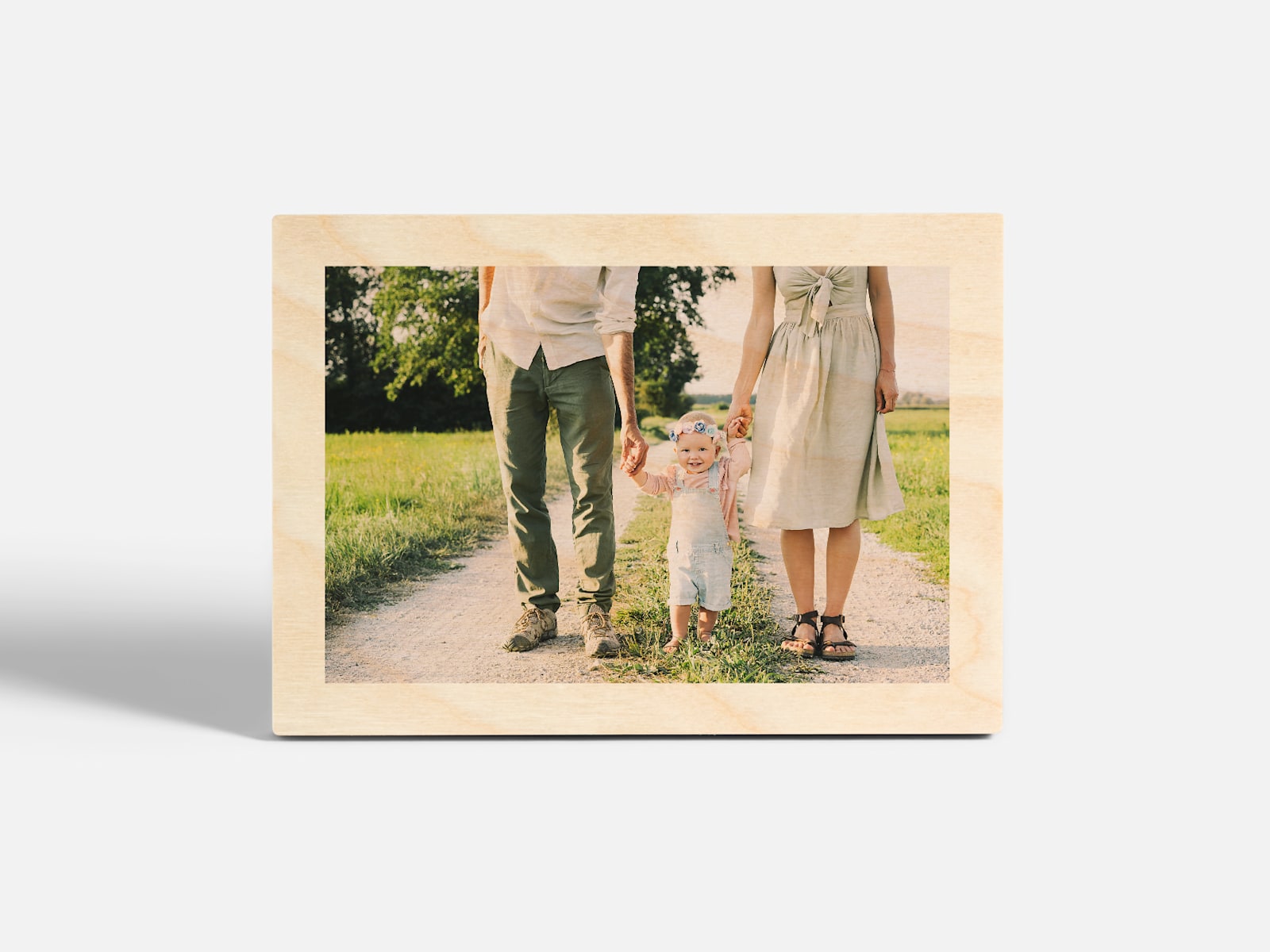 A tabletop wood print featuring a photo of a couple walking hand in hand with their toddler. 