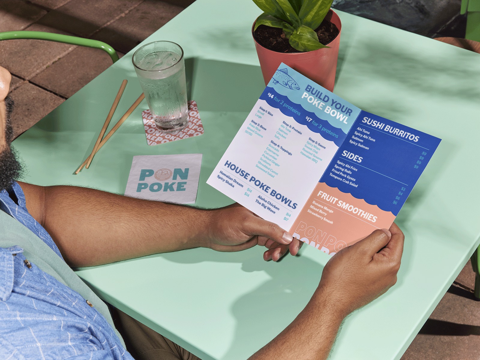 Larger version: A person sitting at a poke bowl restaurant, reading a bi-fold menu.