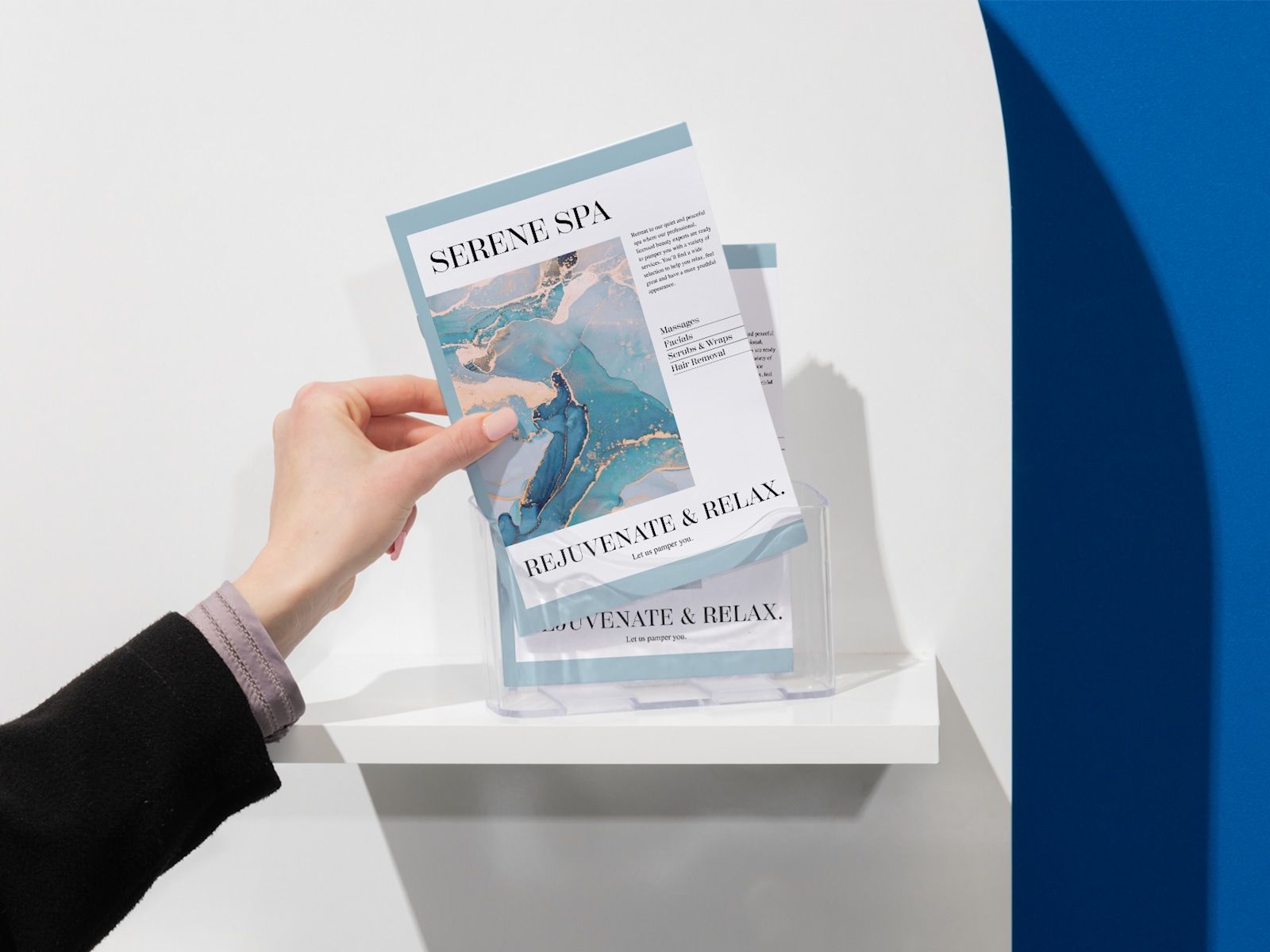 A person takes a saddle-stitch booklet for a spa from a booklet holder. 