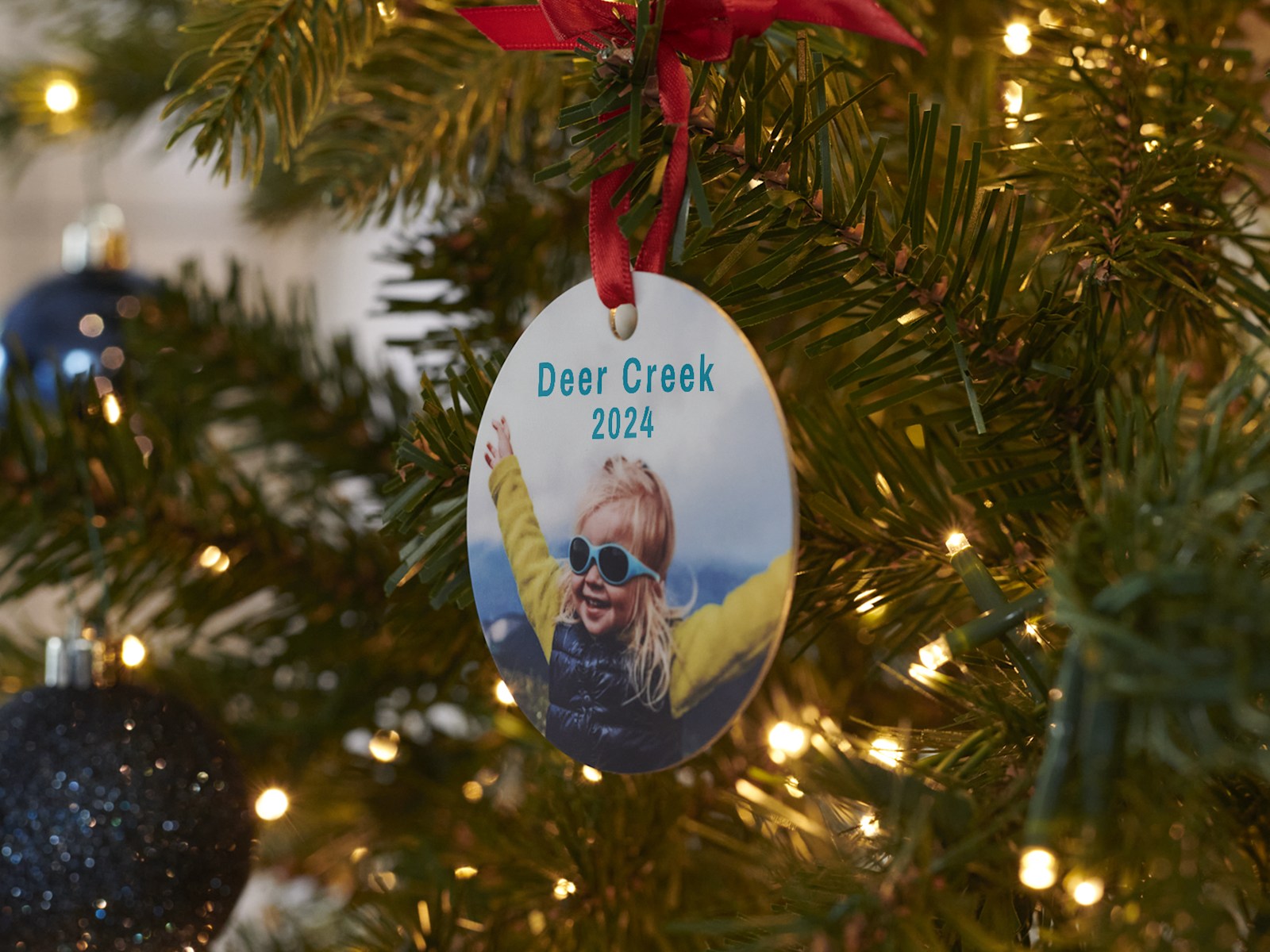 Larger version: A custom ornament on a Christmas tree featuring a photo of a little girl in sunglasses.  
