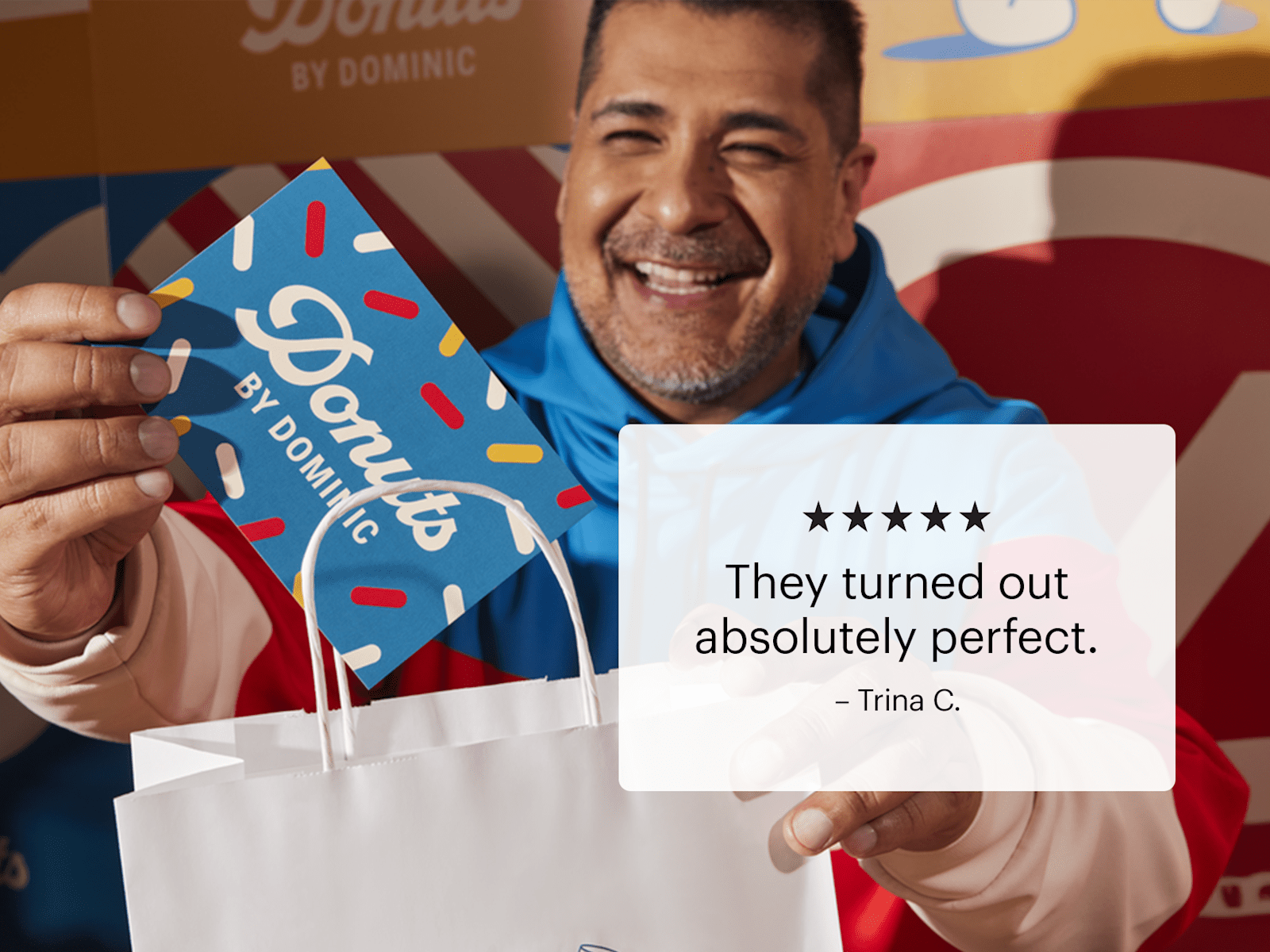 A donut shop owner placing a postcard in a takeaway bag.