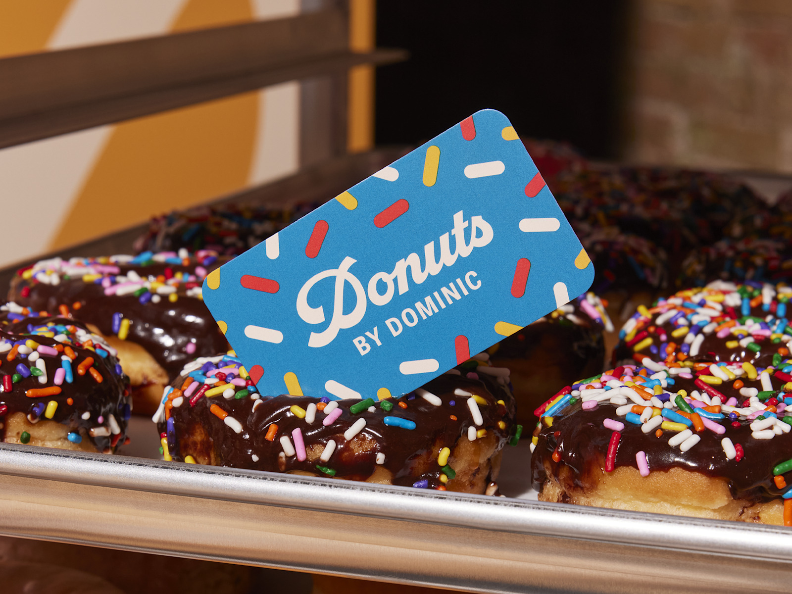 A playful blue business card resting on a tray of donuts.