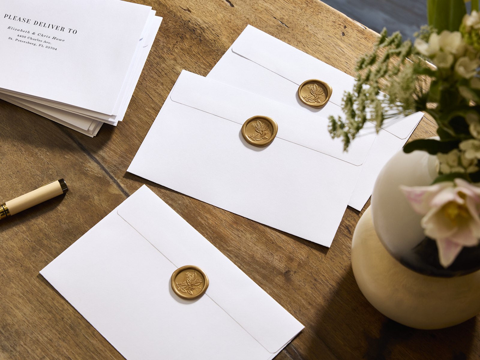 White envelopes sealed with gold-colored, floral wax seals.