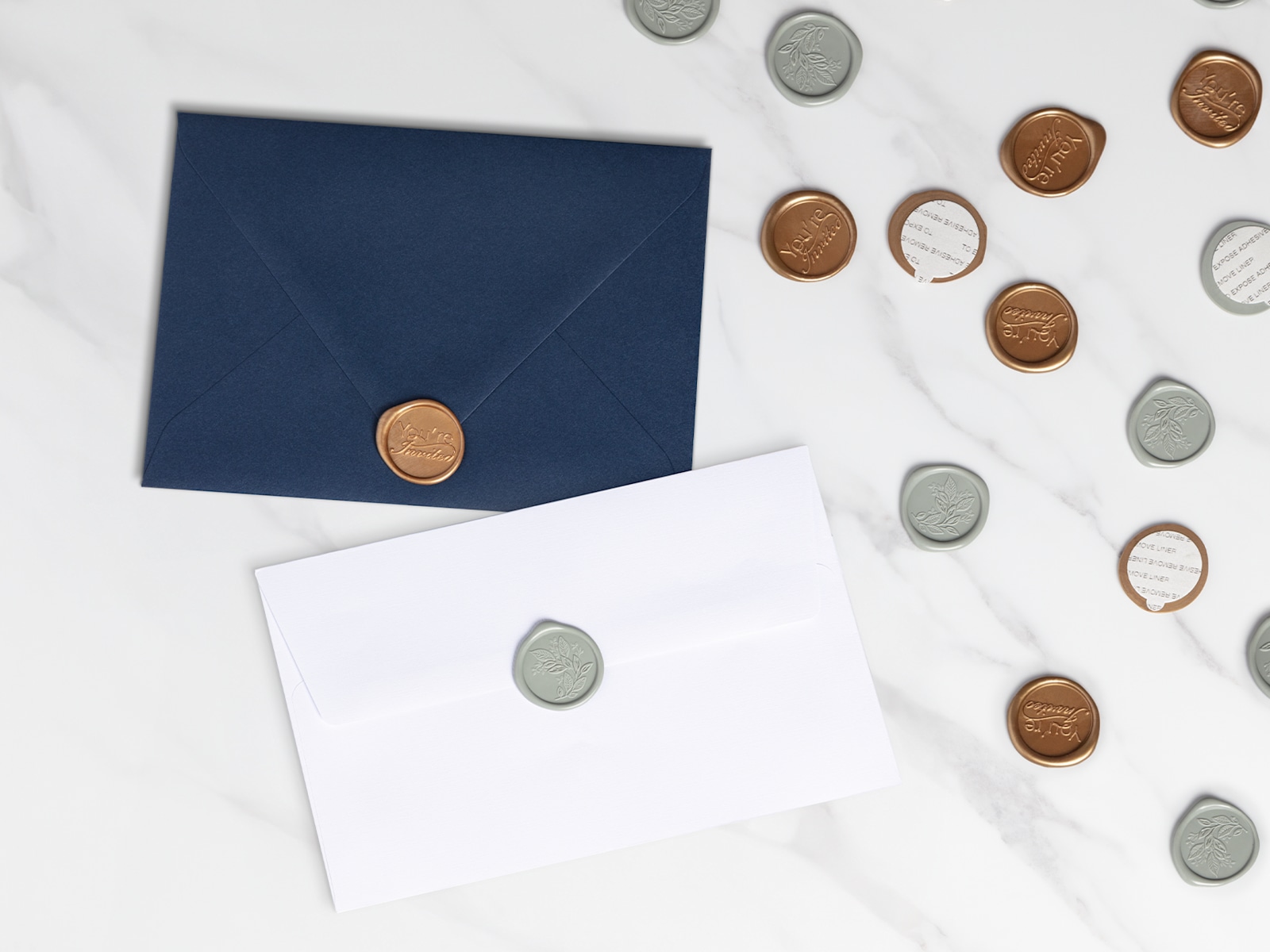 Larger version: Two envelopes topped with gold-colored wax seals resting on a marble tabletop.