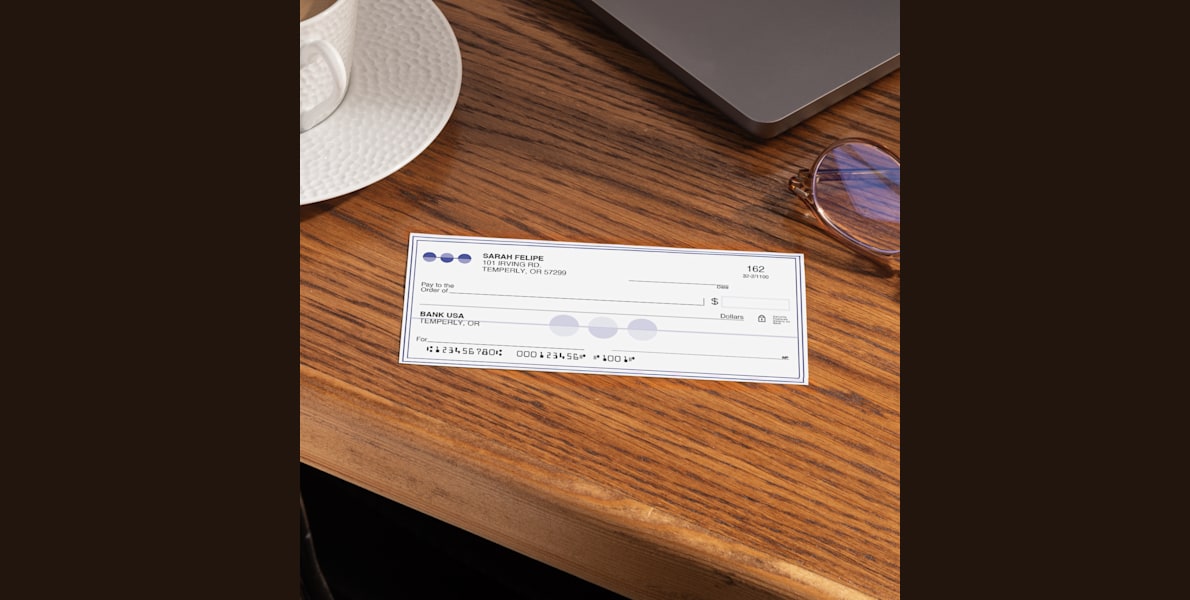 Larger version: A single wallet check on a desk next to a laptop and other office supplies.