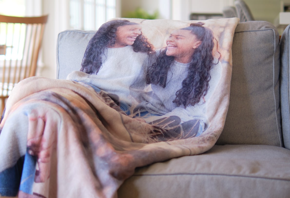 A custom photo blanket with an image of twin siblings rests on a couch.