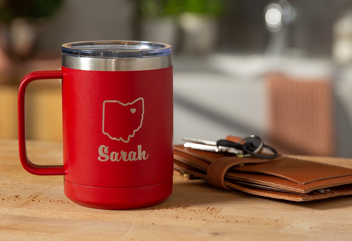 Larger version: Una taza de viaje roja de 15 oz grabada con el nombre Sarah y la de un estado de Estados Unidos. 