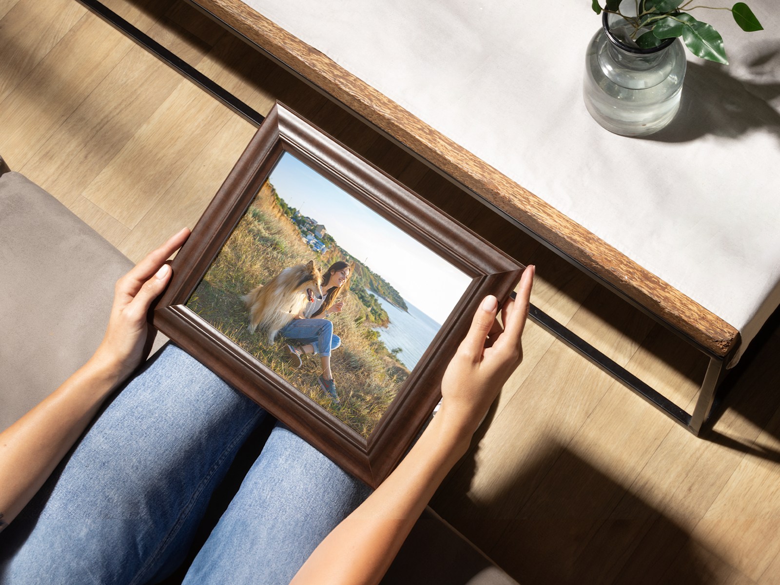 A photo print in a walnut frame is held by a pair of hands.