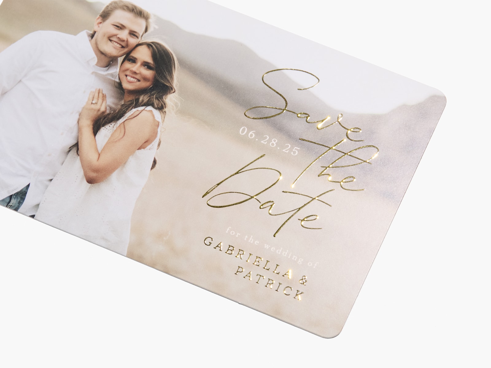 Une carte « Réservez la date » personnalisée présentant une photo d’un couple et des détails à effet métallisé en relief. 