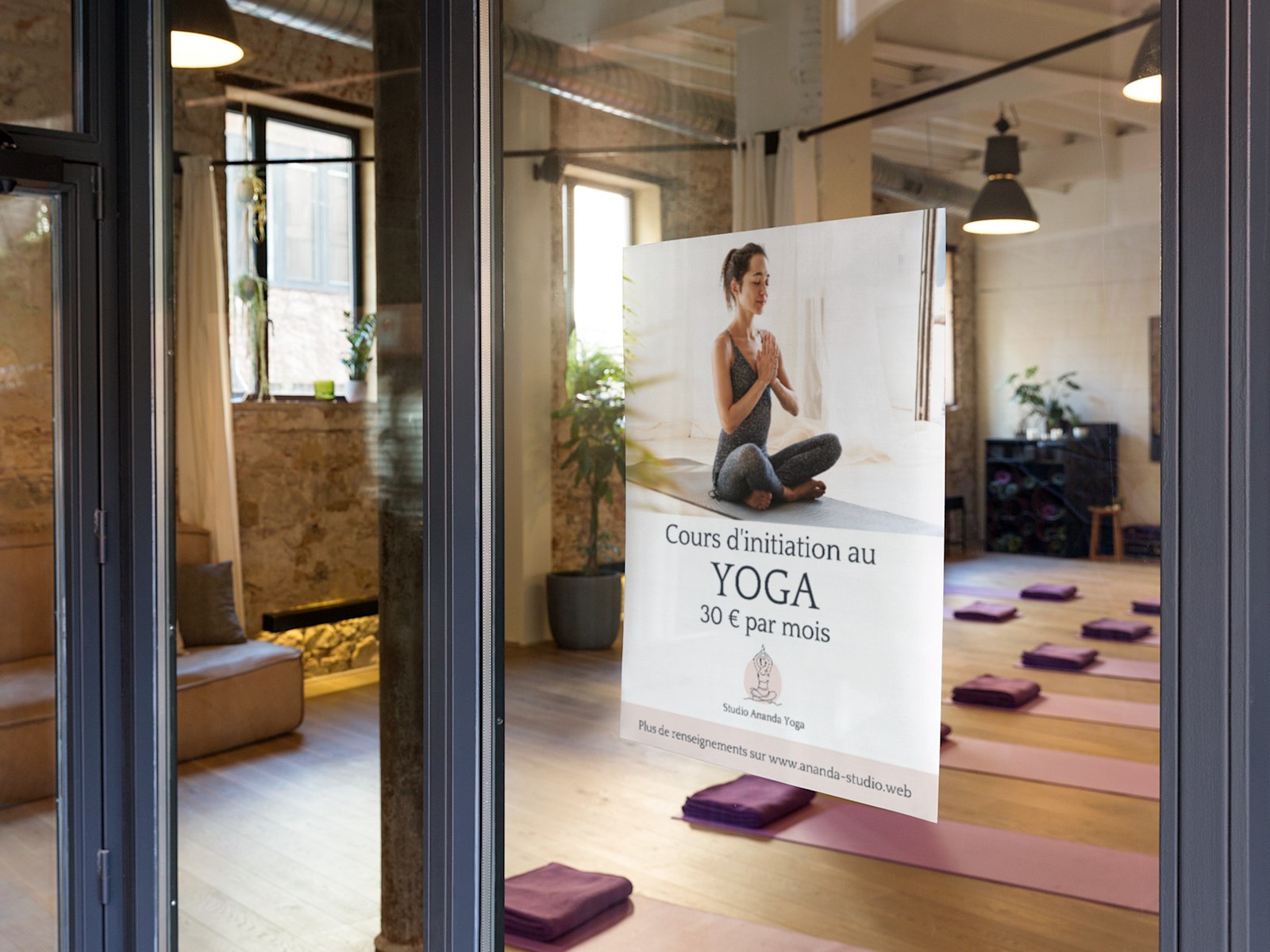 Affiche personnalisée annonçant des cours de yoga, suspendue sur une surface vitrée dans un studio de yoga.