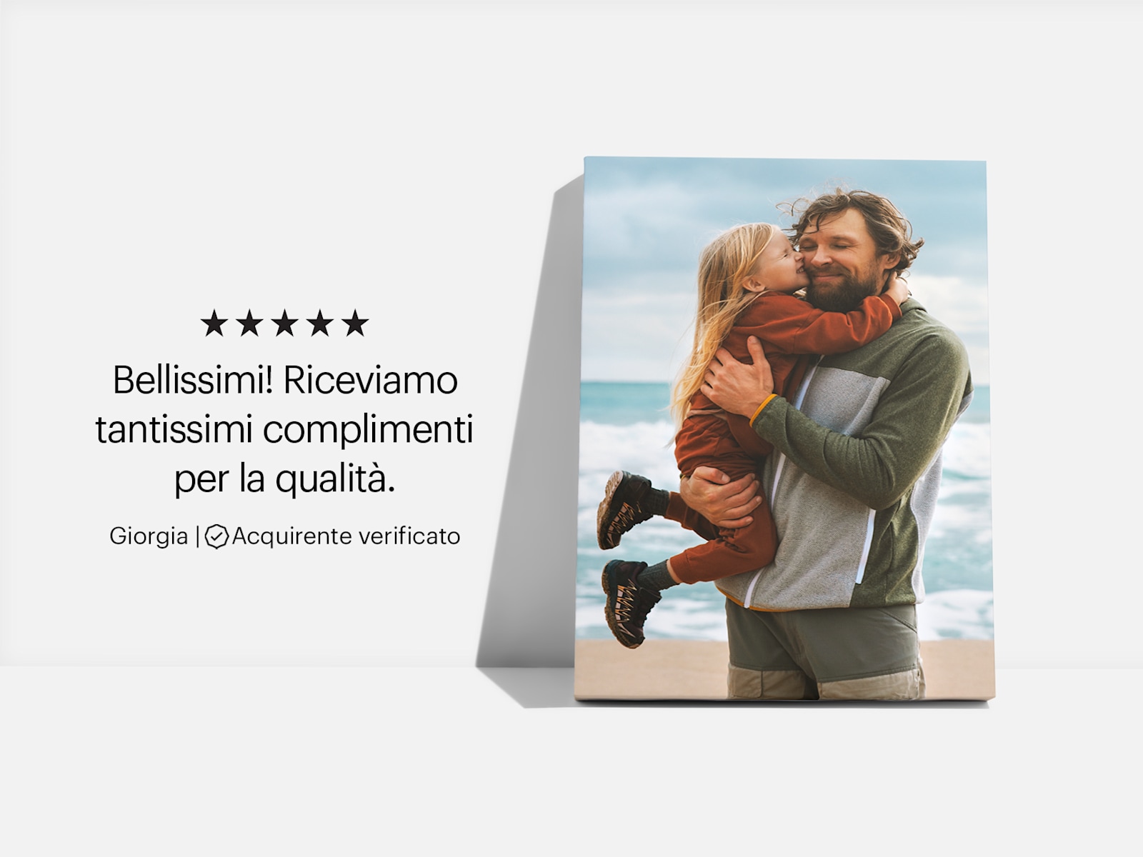Una stampa su tela raffigurante la foto di un padre con la figlia in spiaggia. Accanto c’è la recensione di un cliente: “Bellissima! Continuiamo a ricevere tantissimi complimenti per la qualità!” 