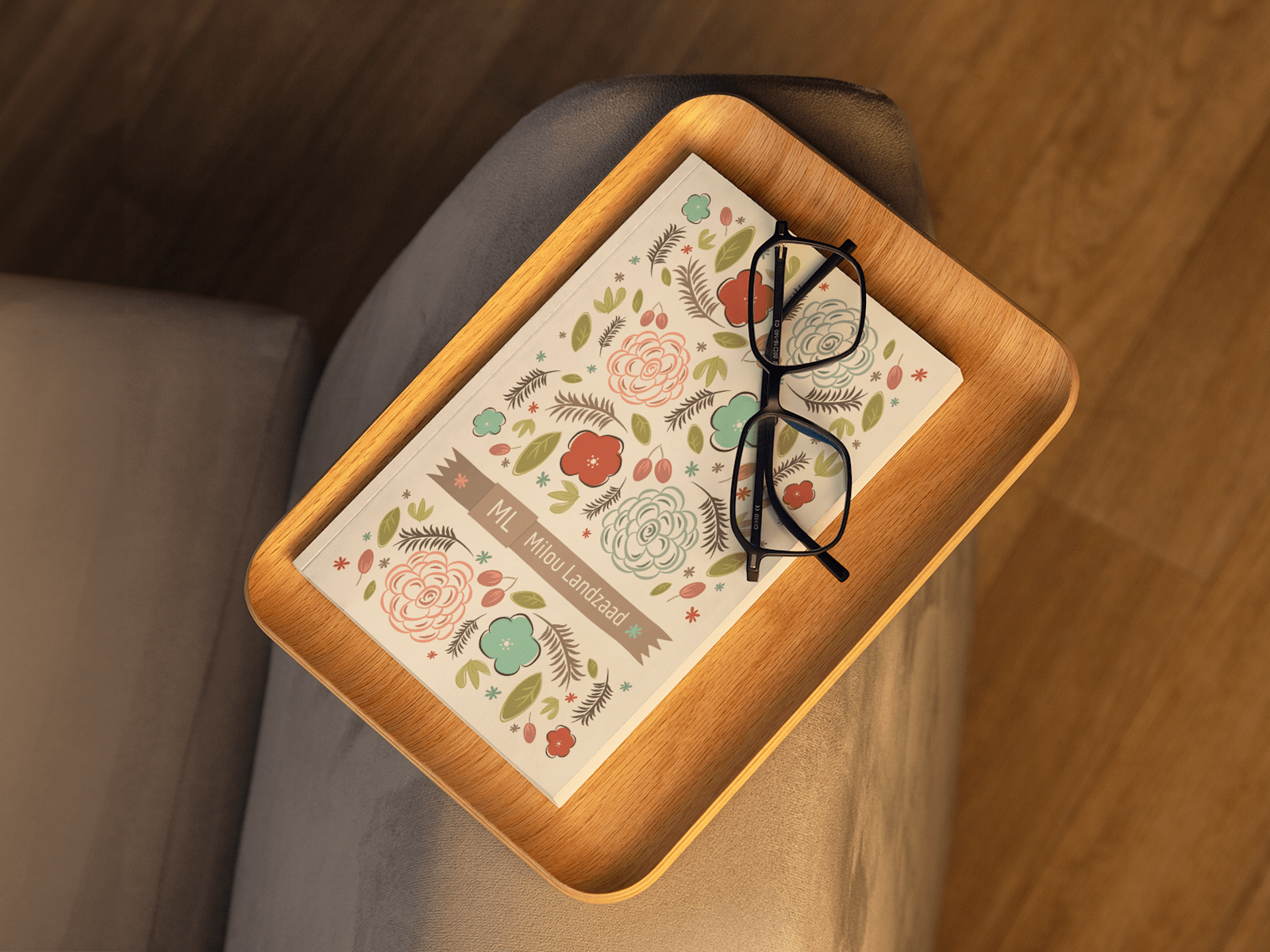 A custom journal with a floral cover design and a pair of reading glasses, sitting on a sofa. 