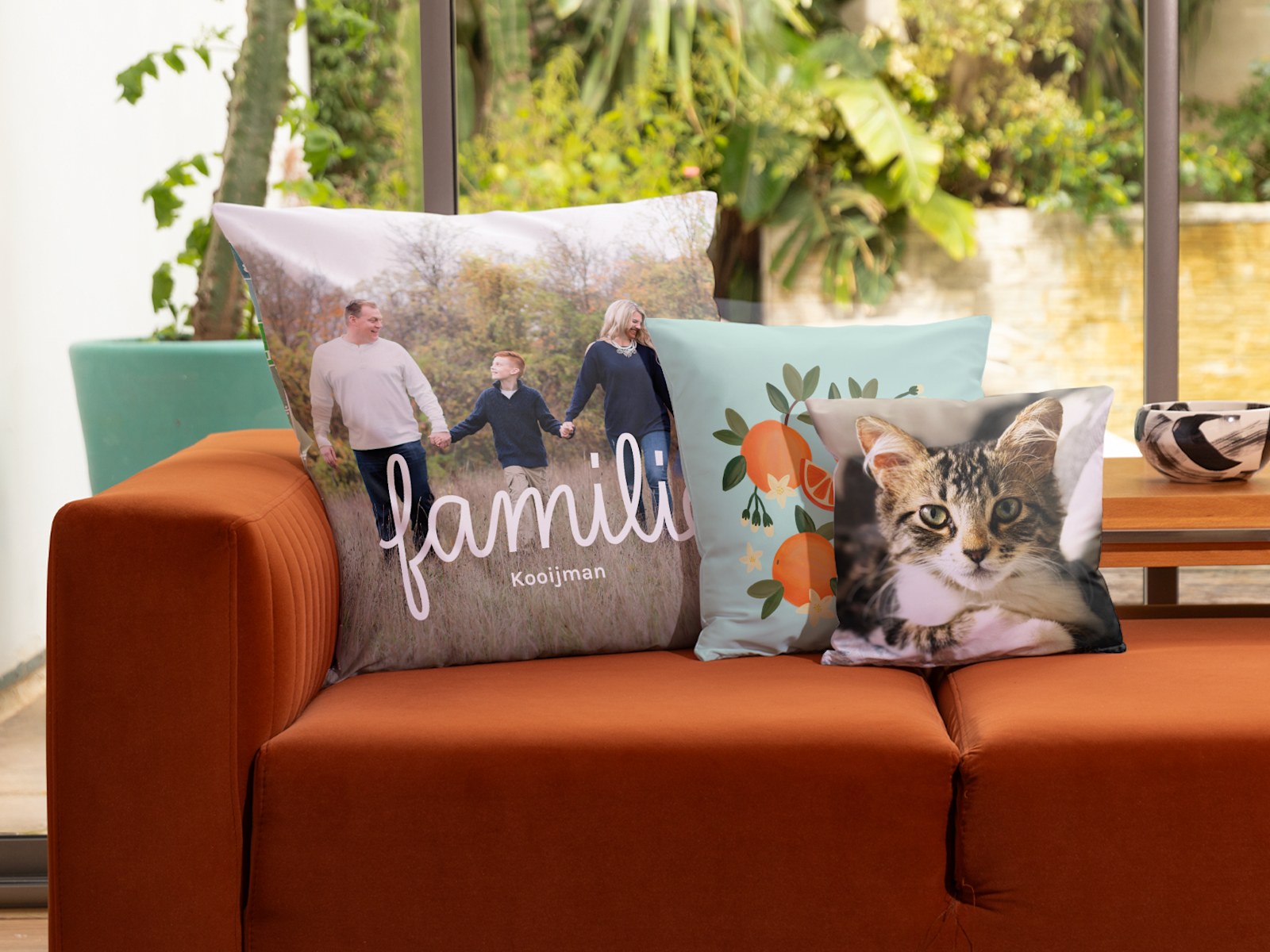 Drie gepersonaliseerde kussens met een foto van een gezin, een afbeelding met sinaasappels en een kattenfoto. 