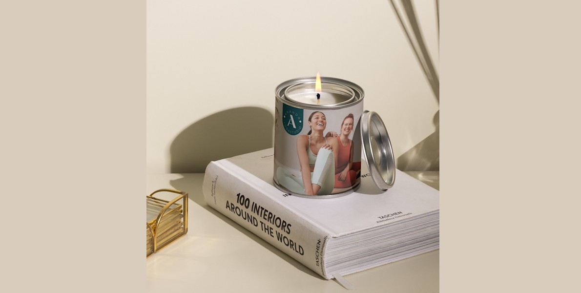 Een bedrukte kaars gepersonaliseerd voor een yogastudio met een bedrijfslogo en een foto van een vrouw in yogakleding. 