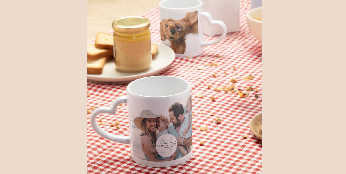 Twee mokken met hartvormig oor op een ontbijttafel. 