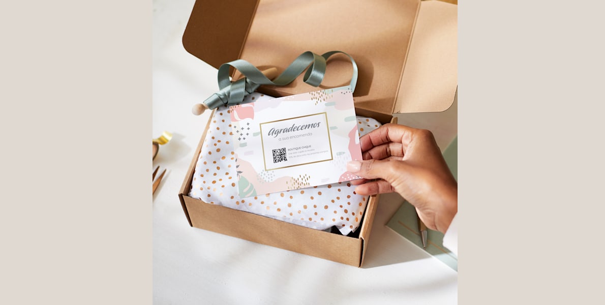 Um cliente segura um postal personalizado de agradecimento entregue com uma caixa de presente.