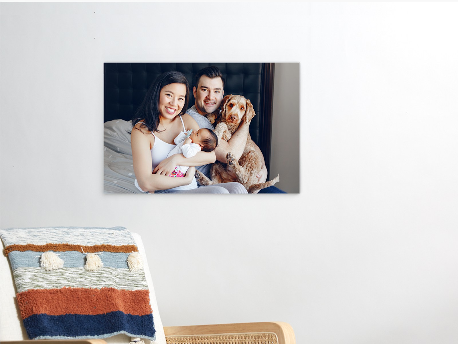 Uma impressão em acrílico que mostra uma fotografia de uma família, com dois pais, um bebé e um cão. 