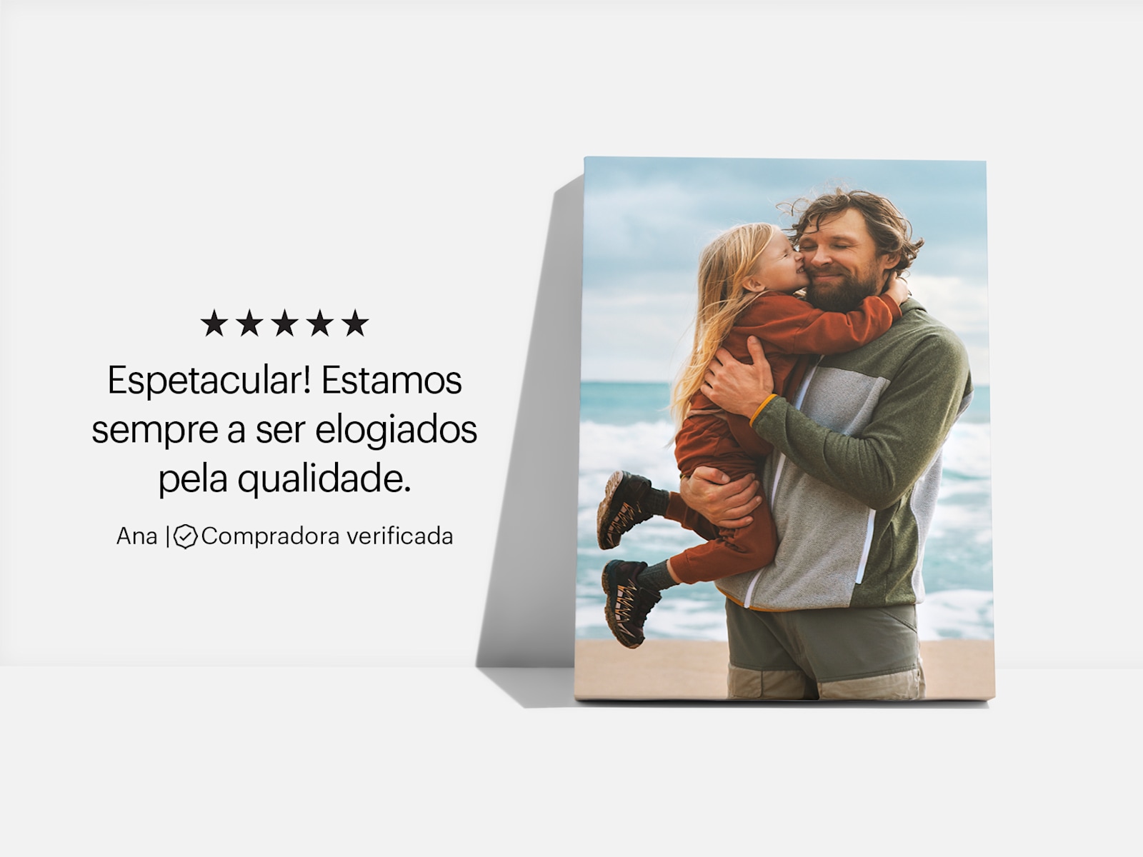Uma tela impressa com uma fotografia de um pai com a filha na praia e a opinião de um cliente: "Espetacular! Estamos sempre a ser elogiados pela qualidade." 