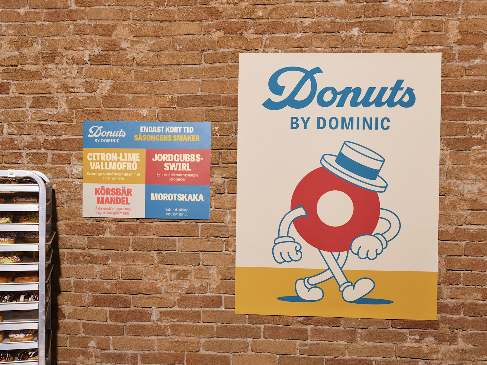 Två affischer från ett donut-företag intill några färska donuts.