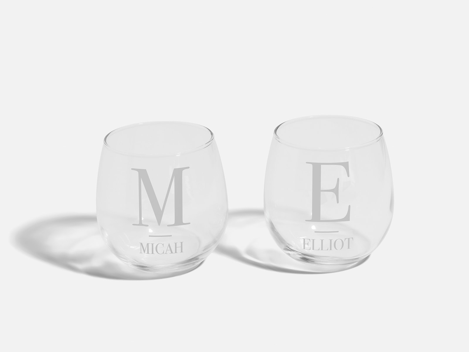 Two stemless wine glasses personalised with monograms and names.