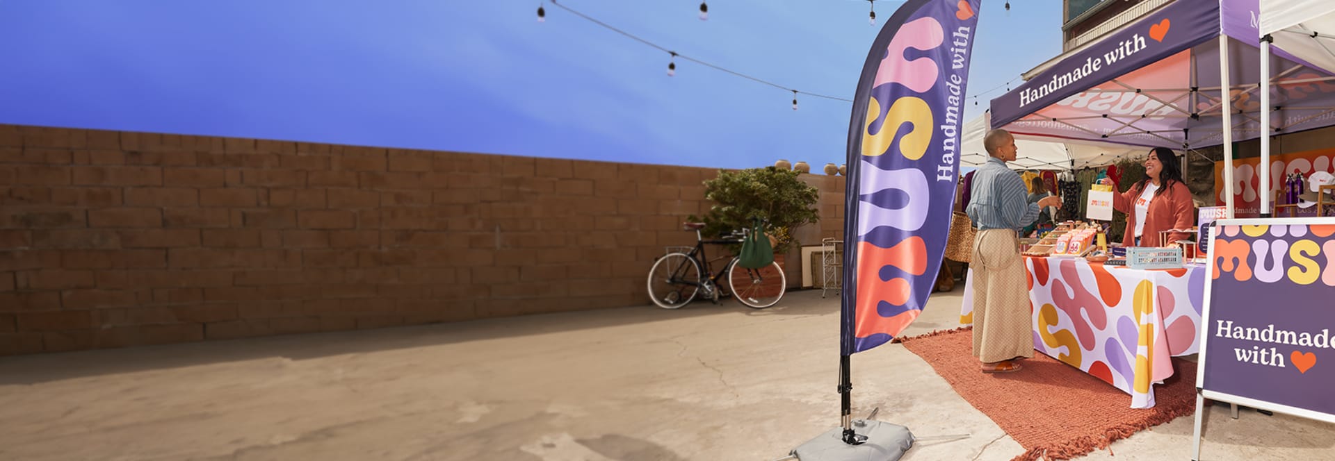 An outdoor market stand, featuring a custom flag, A-Frame sign, tablecloth and tent. 