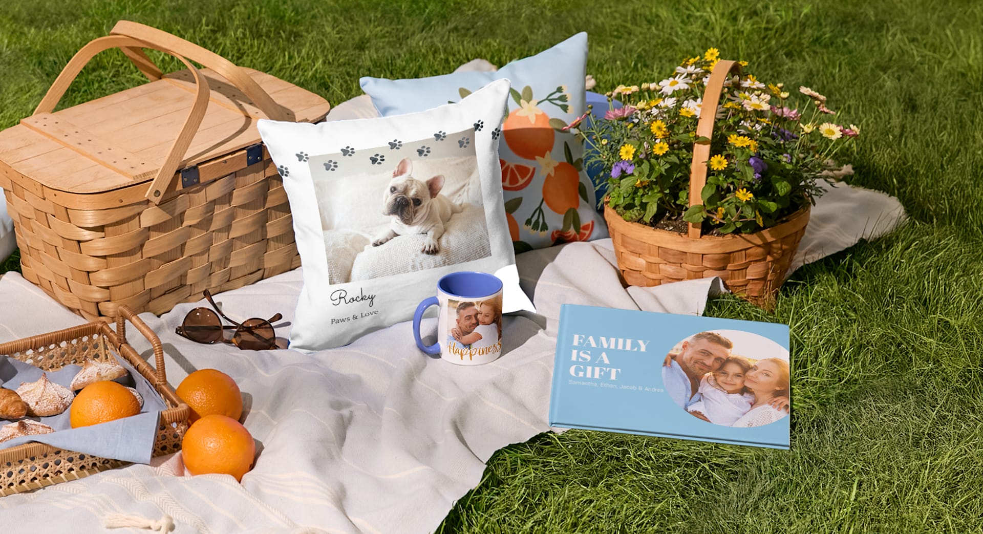 A custom mug, pillow and photo book displayed on a blanket near a picnic basket.